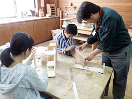 指導員が親子の木工を手伝う様子
